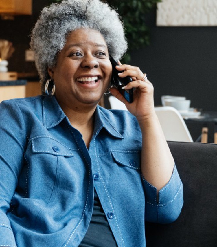 A lady talking on her phone whilst sitting on sofa